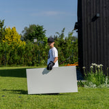 Ett barn bär en skottplatta hockey 120x60 cm på en grön gräsmatta, redo att träna sina hockeyfärdigheter hemma.