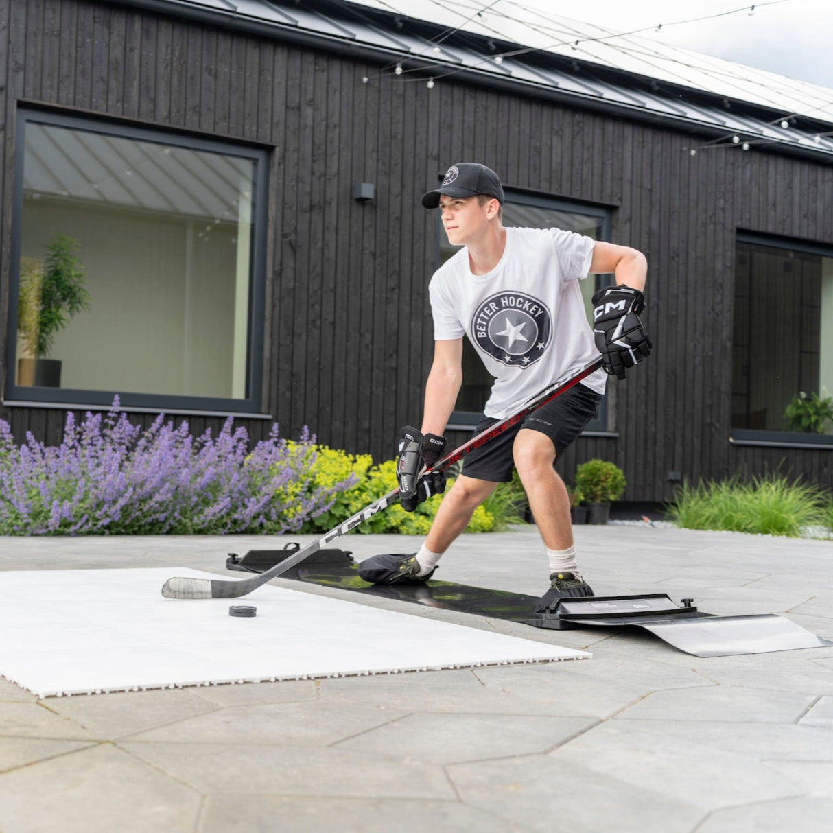 Ung man tränar på en hockey slide board utomhus, med puck och klubb, för att förbättra balans och lateral rörlighet.