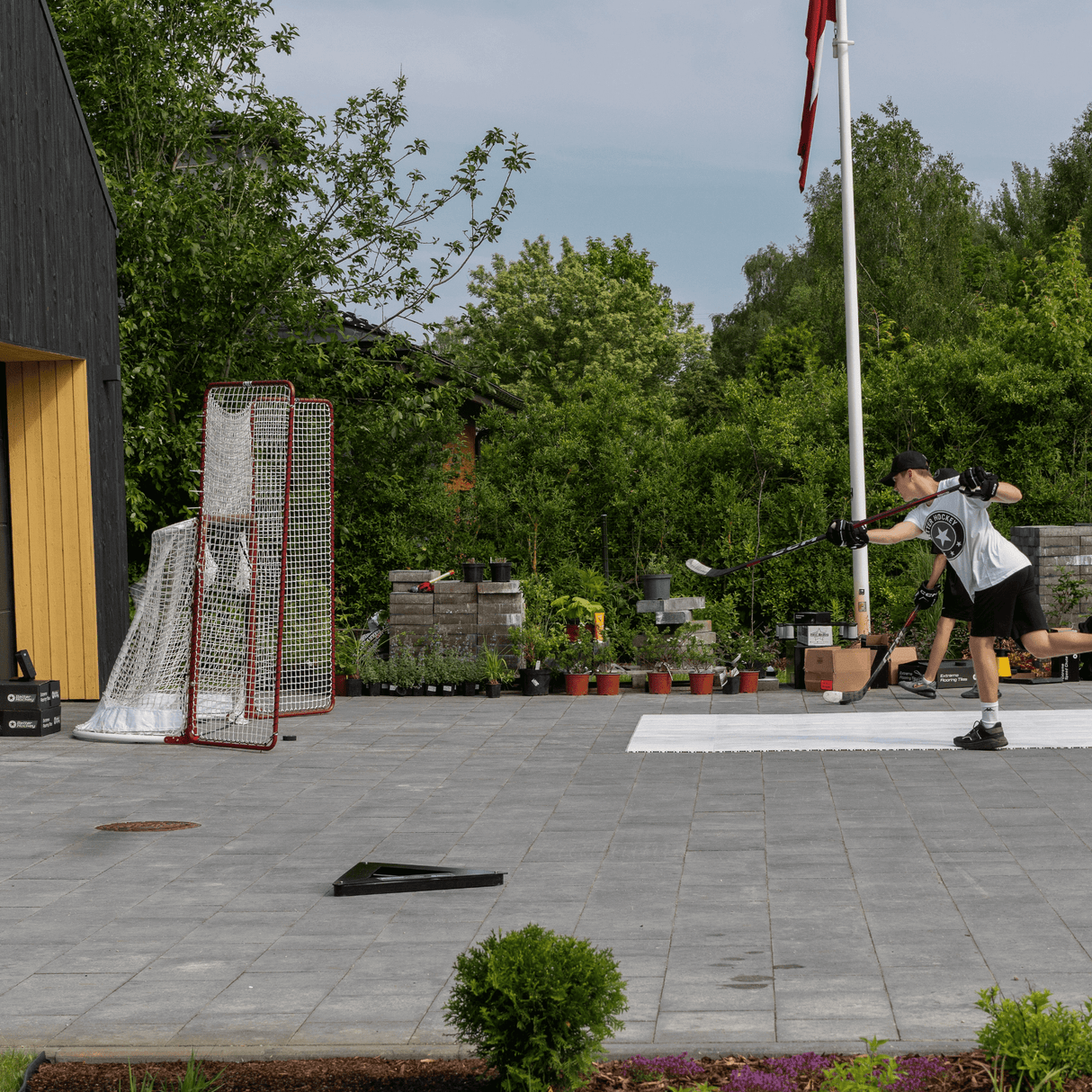 En spelare tränar med en skottmätare och hockey radar i trädgården, riktad mot ett mål.