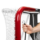 Närbild av en hand som fäster en krok på en målvaktsduk för hockey, med röd målvaktsram och nät i bakgrunden.