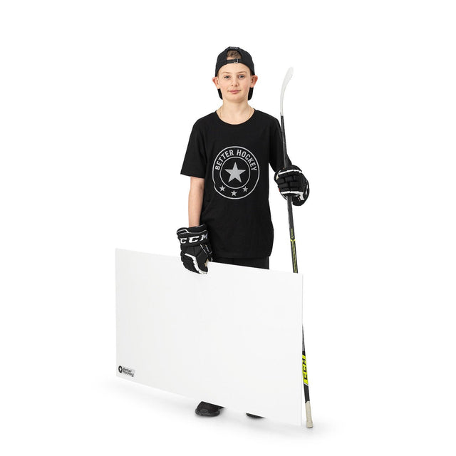 Ung hockeyspelare med skottplatta hockey 120x60 cm, hållande klubba, i svart t-shirt och handskar. Perfekt för träning hemma.