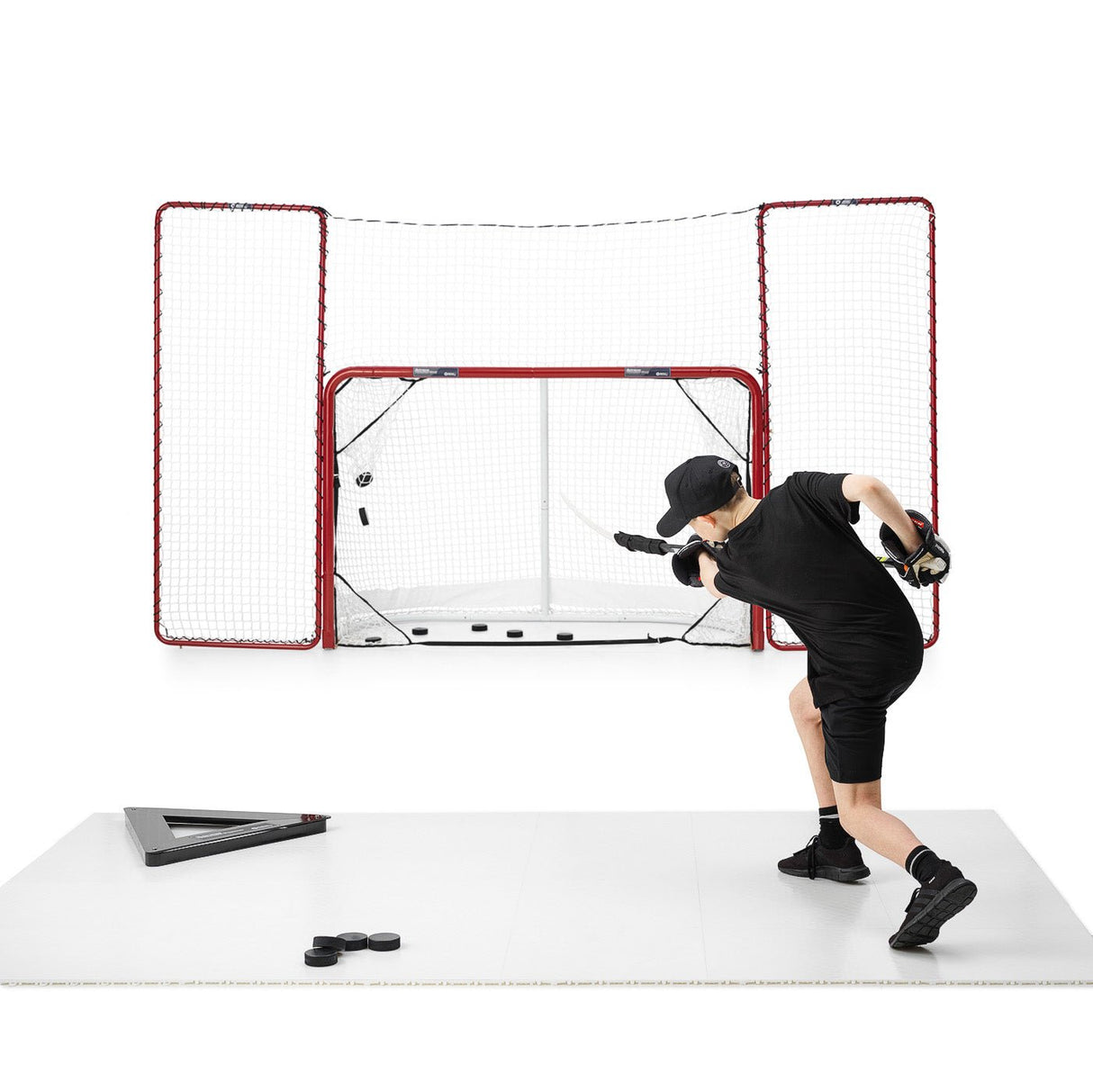 Skottramp teknikpaket hockey i bruk, spelare tränar skott mot mål med puckar på träningsyta.